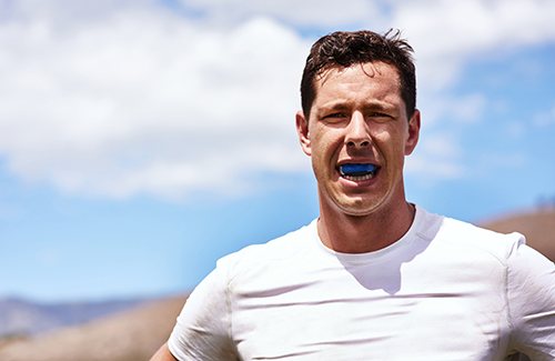 Patient in Grantsville putting in a mouthguard avoid dental emergencies